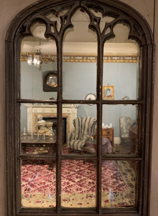 A view into a dollhouse living room through its window.